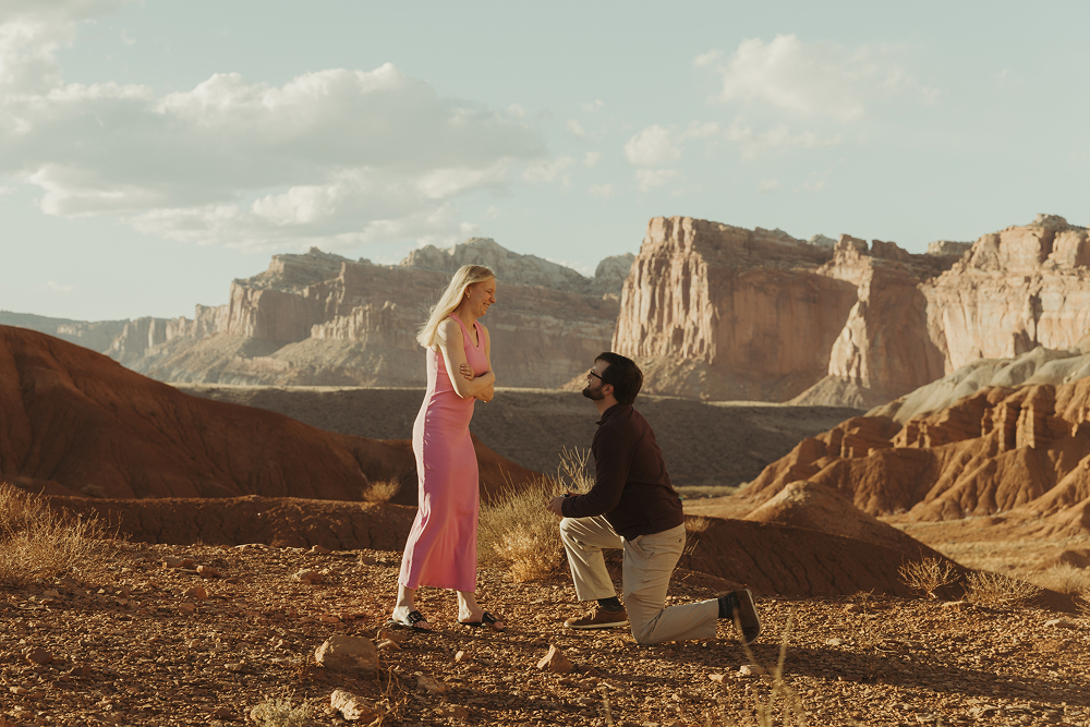 A man proposes to his girlfriend in Capitol Reef National Park. She's completely surprised as he gets down on one knee.